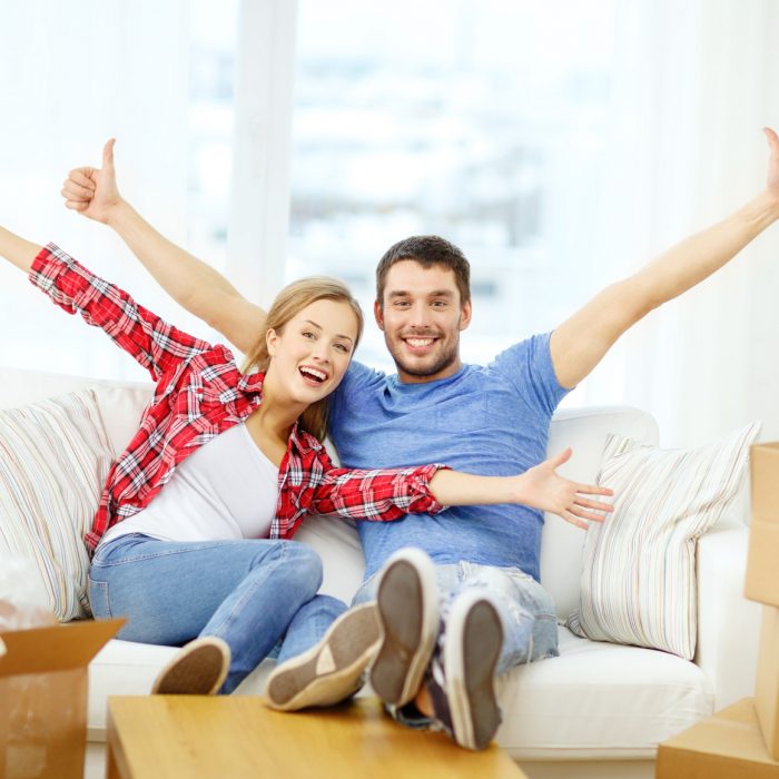 moving, home and couple concept - smiling couple relaxing on sofa in new home